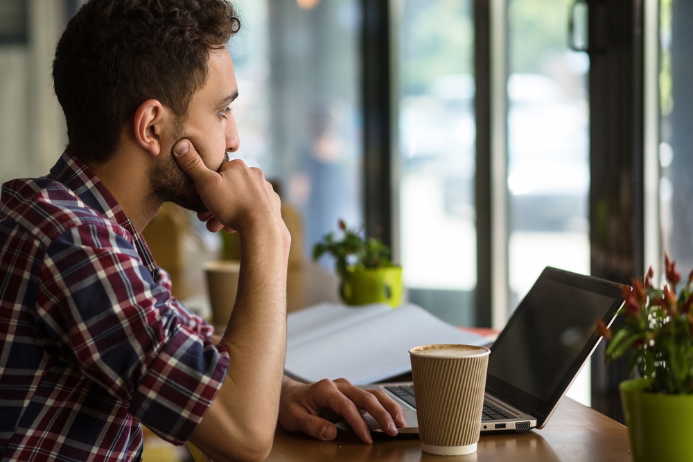 Man with coffee looking at his laptop