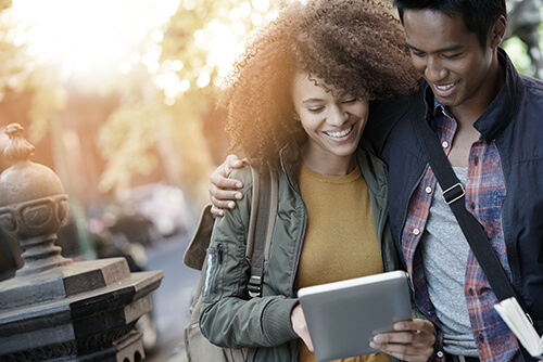 Happy Couple Looking at a Tablet in the City